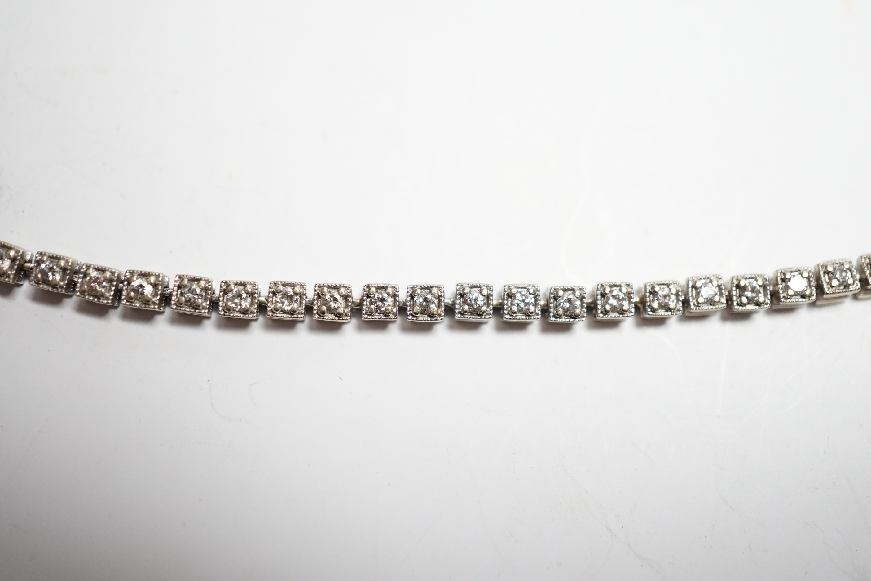 A 750 white metal and diamond line bracelet, set with sixty small stones, 20.8cm, gross weight 12 grams.